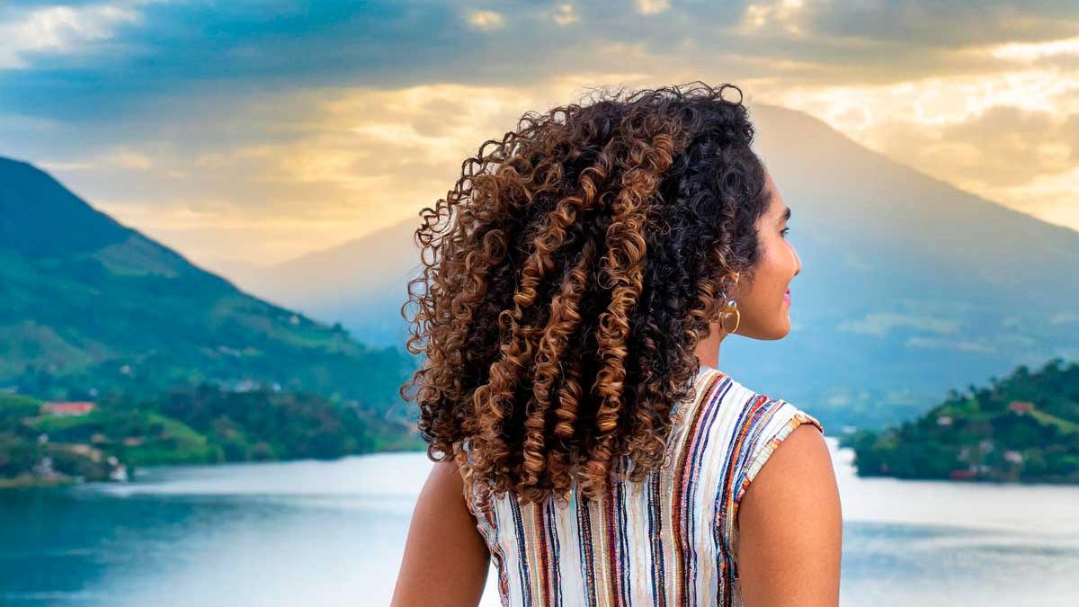 mujer morena con cabello afro vista trasera sobre fondo blanco