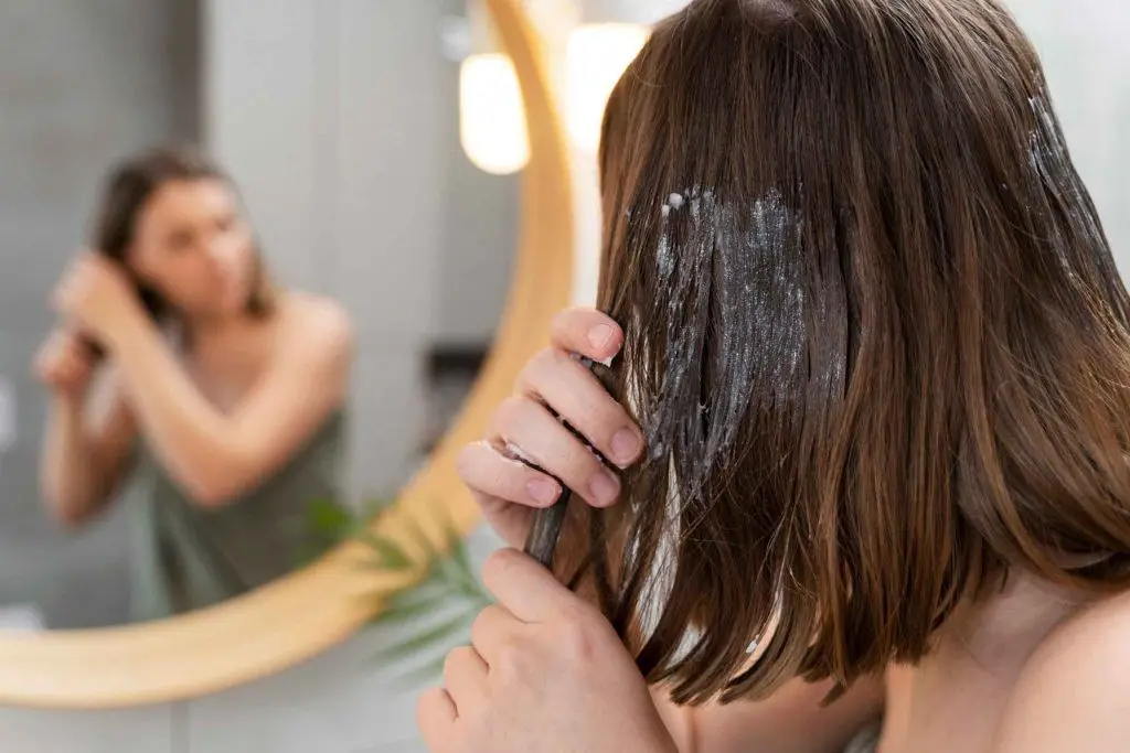 mujer joven que aplica producto anticaspa
