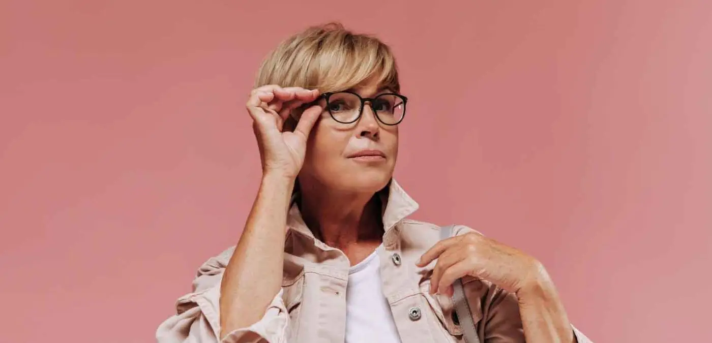 encantadora mujer peinado corto moderno gafas elegante chaqueta ligera mirando camara fondo rosa aislado