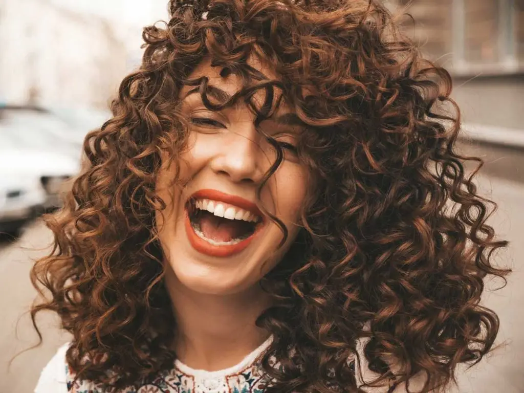 retrato hermosa modelo sonriente con peinado afro rizos
